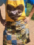 Woman wearing a bibbed apron in bright yellow bib and patchwork skirt with browns and blues