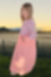 Girl wearing pioneer dress with peach skirt, print bodice with ruffled sleeves
