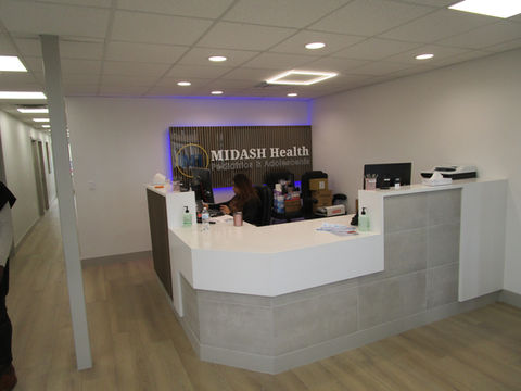 Completed MIDASH Health Front Desk modern style with white counter tops, wood flooring, gray slate and striped wood facade