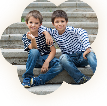 2 hermanos pequeños posando frente a las escaleras de un parque.