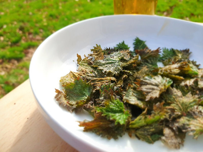 A bowl of stinging nettle crisps and pint of beer