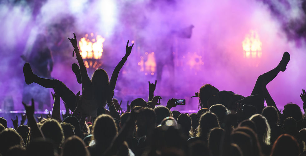 Mandy Madison and "Axe," the guitar player for the band, crowdsurf in front of a misty purple stage.