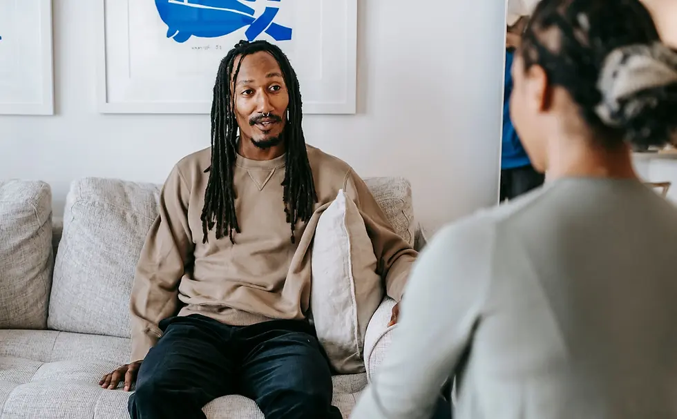 Middle-aged Black man with long hair sitting on a couch facing this therapist.