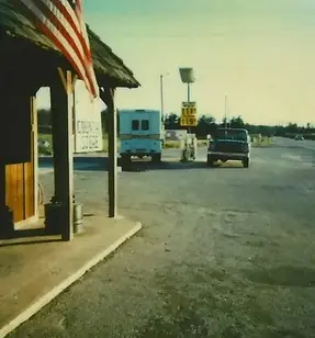 the location when it was a gas station in the 80s, viewed from the side of the building looking at cars pumping gas in the lot.