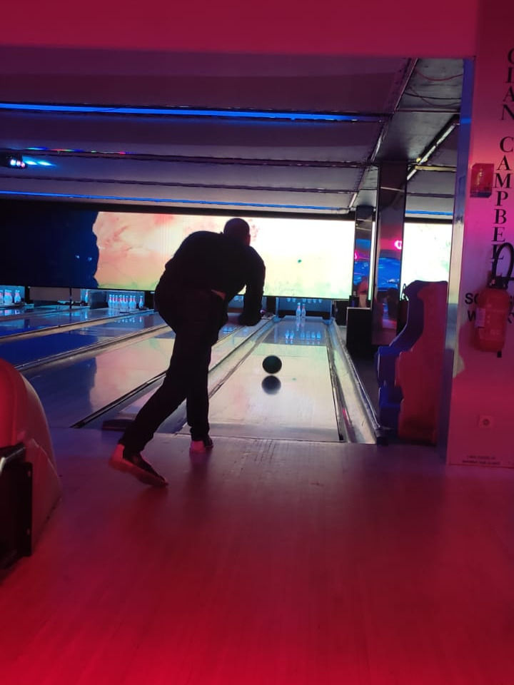 Une personne debout, de dos, en train de lancer une boule de bowling