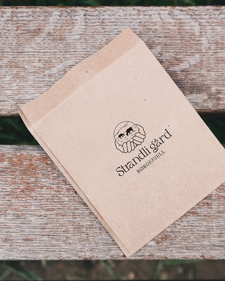 Papirpose med Strandli gård sin logo
