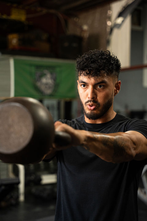 a man in a black shirt is lifting a kettlebell