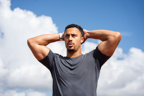 a man in a gray shirt has his hands behind his head