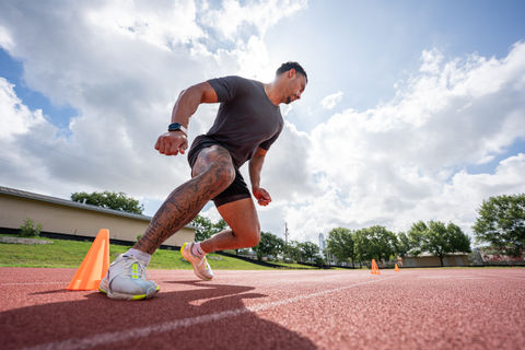 a man with a tattoo on his leg is running on a track