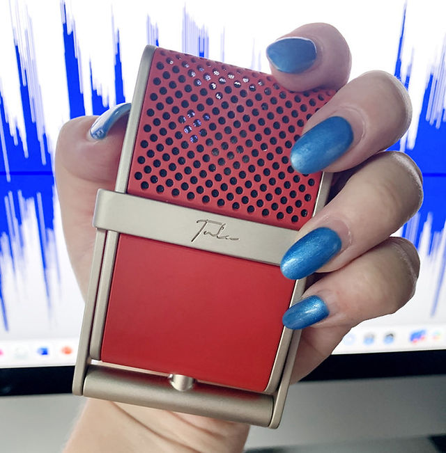 Hand with bright blue nails holding red Tula microphone.