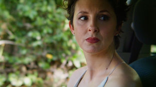 Close-up of a woman looking pensive, set against a blurred green background. "TRAVEL PLANS" title and credits overlay the image.
