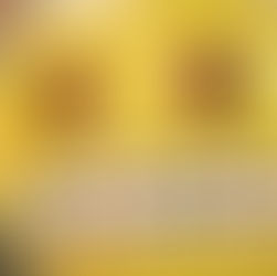 Yellow emoji balloon with large eyes and grid smile, floating indoors. Background has blurred colors, creating a lively atmosphere.