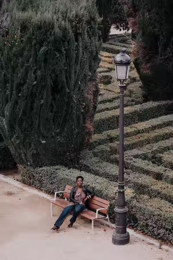 Female portrait in the Sabatini Gardens in Madrid with sculpted hedges in the background.