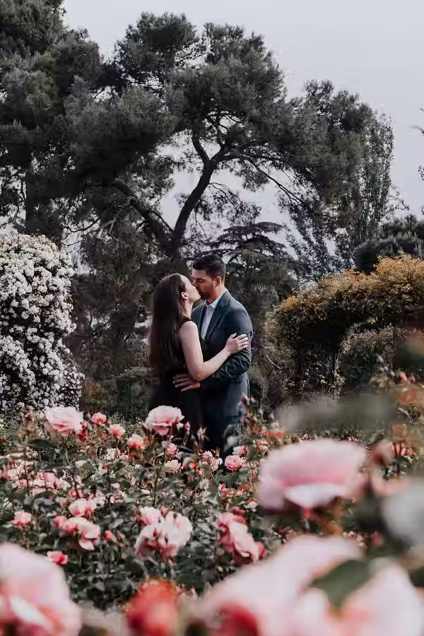 A romantic couples photoshoot, kissing in the La Rosaleda garden of Retiro Park in Madrid.