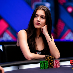 Alexandra Botez seated at a poker table with stacks of chips during a televised poker event.