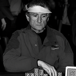 Jack Keller playing poker in a black-and-white casino photograph, wearing a visor and reaching toward stacks of poker chips.