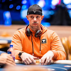Matt Berkey wearing an orange hoodie and black cap while seated at a poker table during a live tournament.
