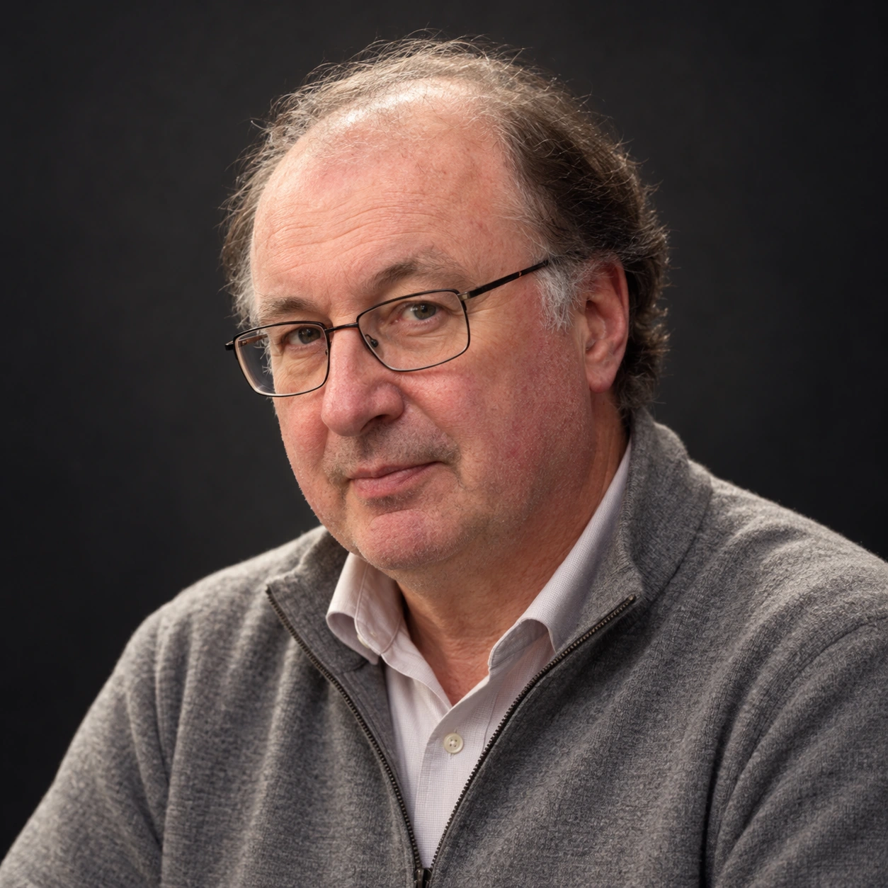 Editorial illustrated portrait of Padraig Parkinson with glasses and thinning gray hair against a dark background.