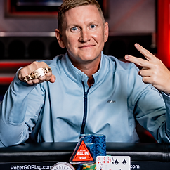 Ben Lamb at a poker table displaying a WSOP bracelet with poker chips and cards in front of him.