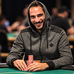 Julien Sitbon in a gray hooded jacket seated at a green felt poker table with stacks of chips.