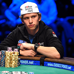 Peter Eastgate seated at a poker table with stacks of chips, wearing a white PokerStars.net cap and black hoodie during tournament play.