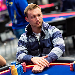 Aliaksei Boika seated at a poker table during a live tournament with stacks of chips in front of him.