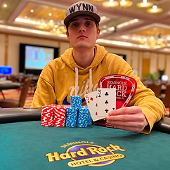 Poker player Jeremy Becker holding playing cards behind stacks of tournament chips at Seminole Hard Rock.