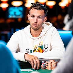 Laszlo Bujtas seated at a poker table in a white hoodie, with sunglasses on his head and stacks of tournament chips in front of him.