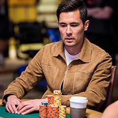 Galen Hall seated at a poker table with stacks of tournament chips and a coffee cup during live poker play.