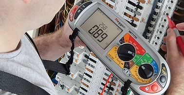 Electrician's hands holding a Megger MFT performing installation testing