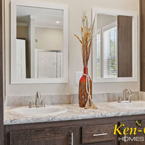 Bathroom sinks and mirrors with Ken-Co Homes branding on display.