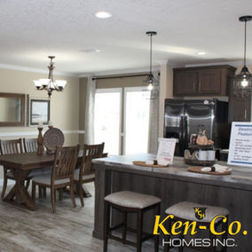 Dining room with table, chairs, art, and Ken-Co Homes text in view.