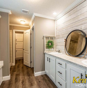 Bathroom with double sinks, mirror, and KenCo Homes logo on the cabinet.