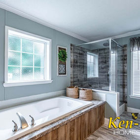 Bathroom with tub and shower, Ken-Co Homes, light blue walls, natural light.