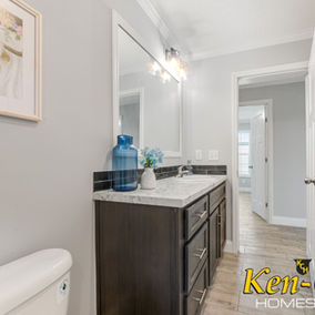 Bathroom interior with vanity, sink, mirror, and Ken-Co Homes Inc. sign.