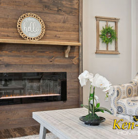 Rustic living room with fireplace, hello sign, and Ken-Co Homes branding.