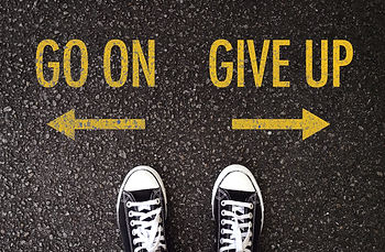 Nell'immagine si vedono due scarpe sulla strada di fronte ad una scritta: "Go On", "Give Up"