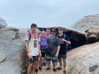 family photo of five people standing among large rocks outdoors, landscape