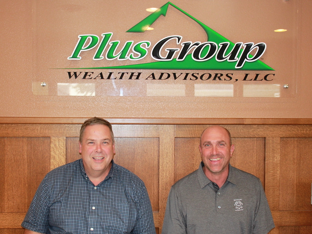 Jay Lauer and Brent Neis by new Plus Group Wealth Advisors Sign.