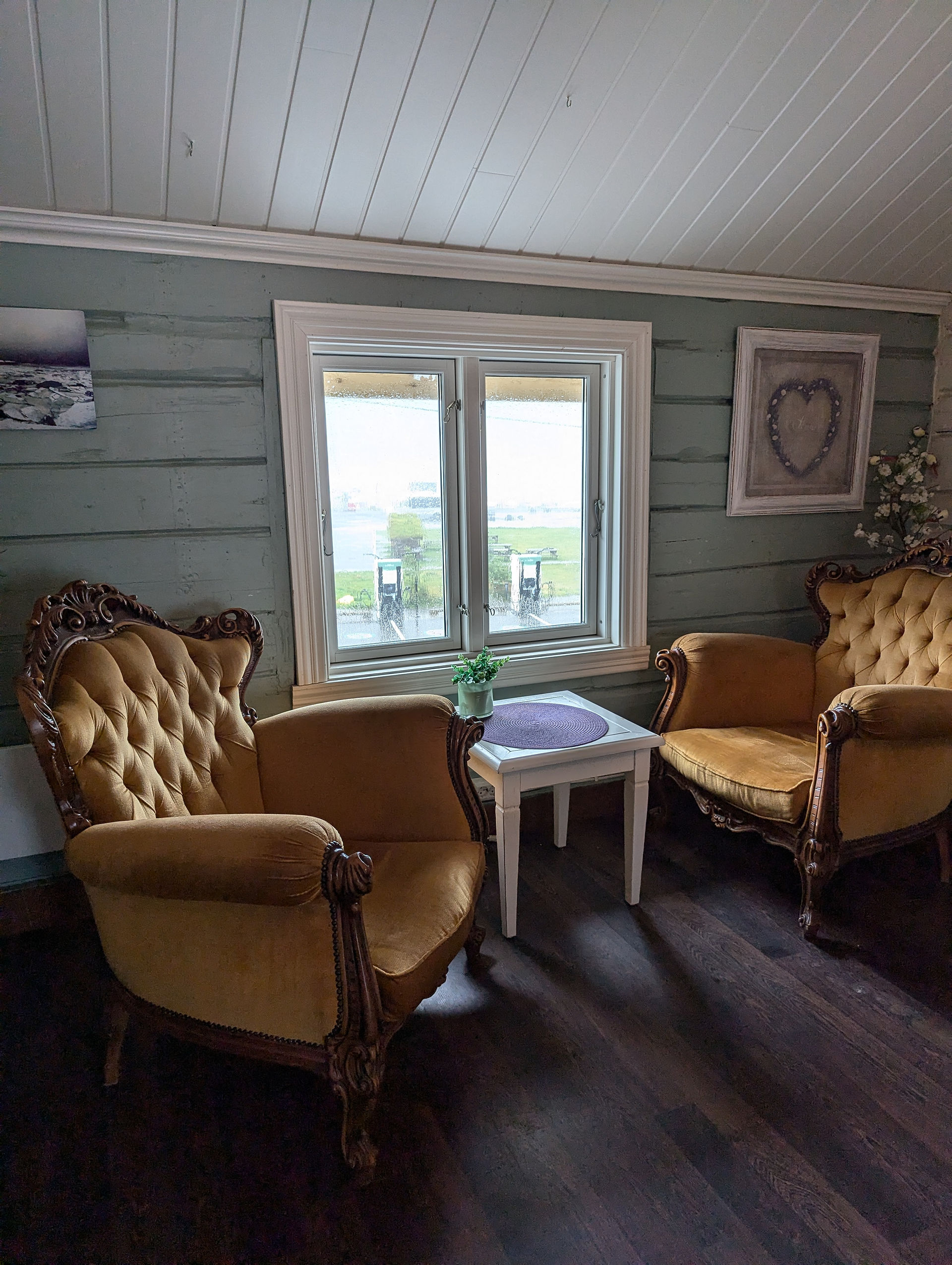 Vintage velvet chairs and a side table in front of a rainy window.