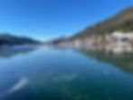 Belo jezero: Zamrznjeno jezero z modrim nebom, zasneženimi gorami in mestom ob obali. Cerkev izstopa, ozračje je mirno in hladno.
