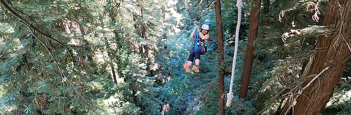 Sophia on a zip line in a forested area