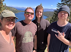 Sophia with her husband and two sons in front of a lake