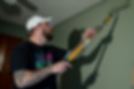 Man painting a green wall using a roller.