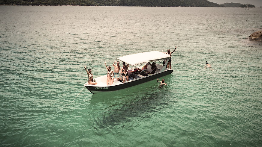 Grupo de pessoas acenando em barco de passeio no mar.