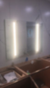 Bathroom mirror with vertical lights above open cabinets