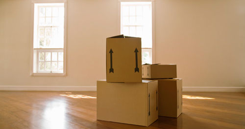 Gestapelte Umzugskartons in leerem, sonnendurchflutetem Raum – Symbol für Abschied, Loslassen und den Beginn eines neuen Kapitels.