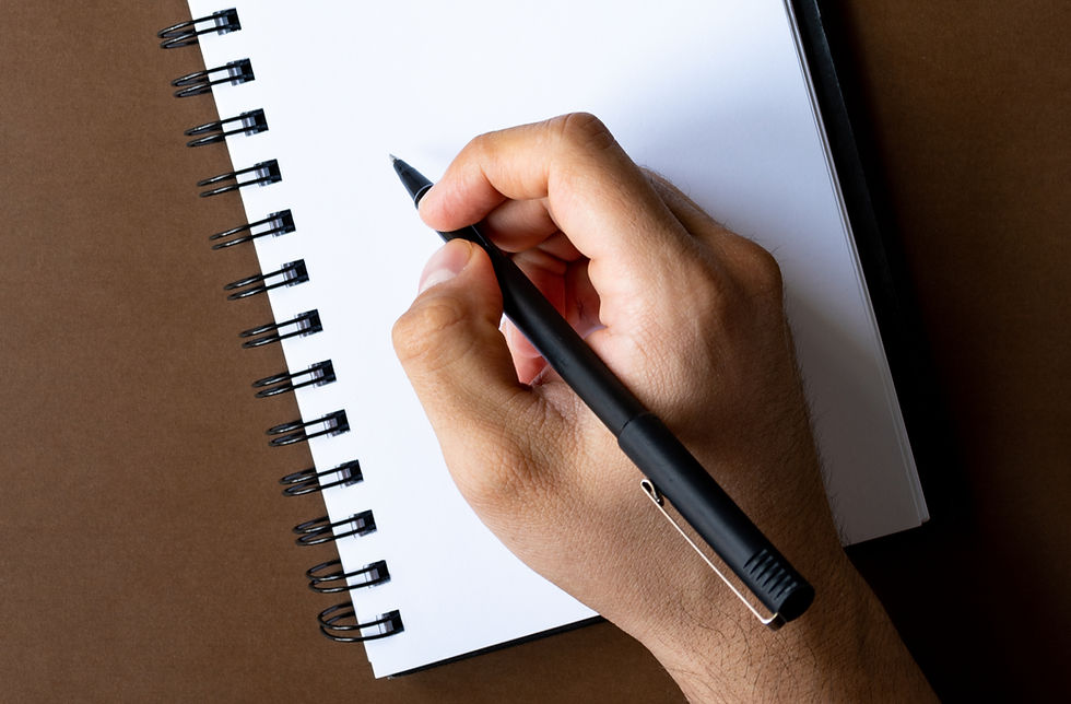 Hand schreibt mit einem Stift in ein leeres Notizbuch – Symbol für die bewusste Lenkung von Gedanken und ihre heilende Kraft.