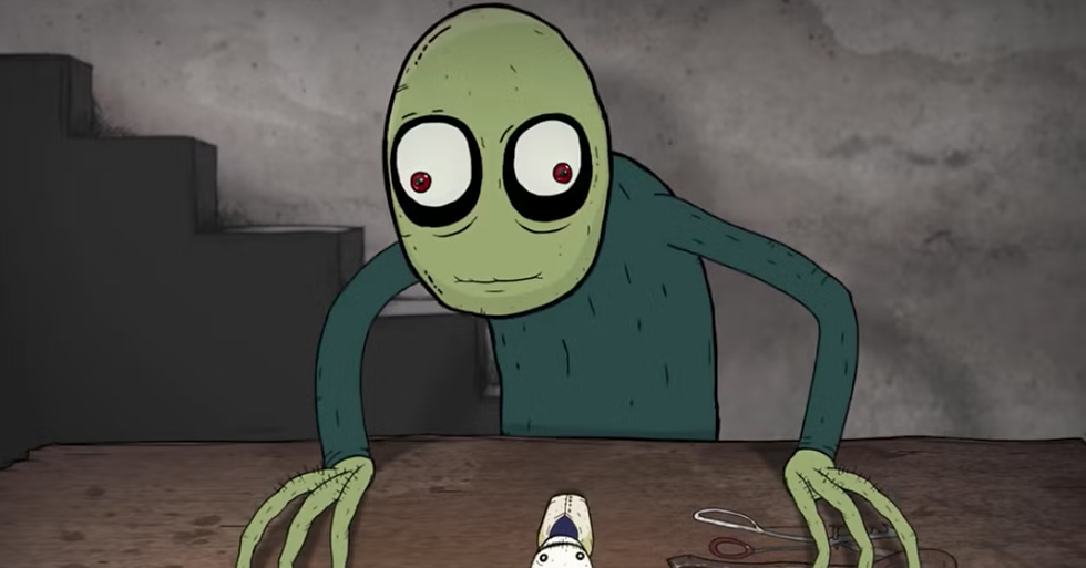 Green character with red eyes leans over a table with a spoon and toy figure