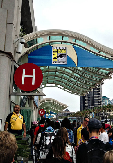 Entrada do Hall H na San Diego Comic-Con 2024 com multidão de fãs em fila, segurança uniformizado e sinalização oficial do evento com logo Comic-Con International
